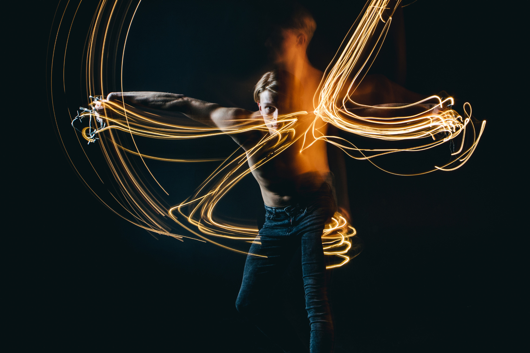 Man with arms spread out with long exposure light lines